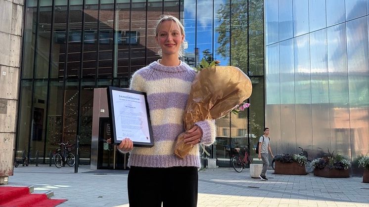 Dansstipendiat My Primbom med diplom och blombukett framför Kulturkvarteret
