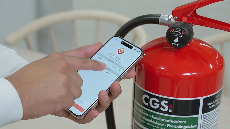 Brandsläckare med sensor bredvid mobilapp som visar realtidsdata och larm.