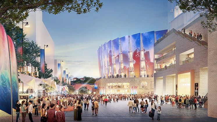 Ett torg där en mängd olika människor rör sig. I bakgrunden en arenabyggnad i tegel och med projiceringar på fasaden.