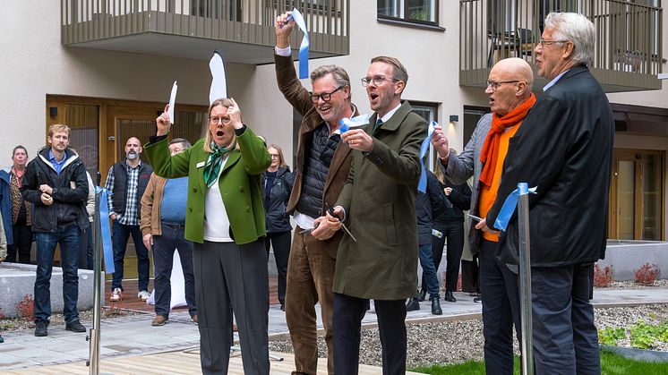 Fem personer har just klippt ett invigningsband på innergården till kvarteret Ananasen med publik runt omkring.