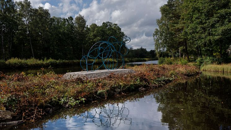 Skulptur på smal landremsa i vattendrag.