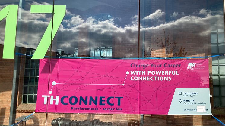 Ein pinkfarbenes Banner mit der Aufschrift THCONNECT hängt in der Glasfront von Halle 17 auf dem Campus der TH Wildau.