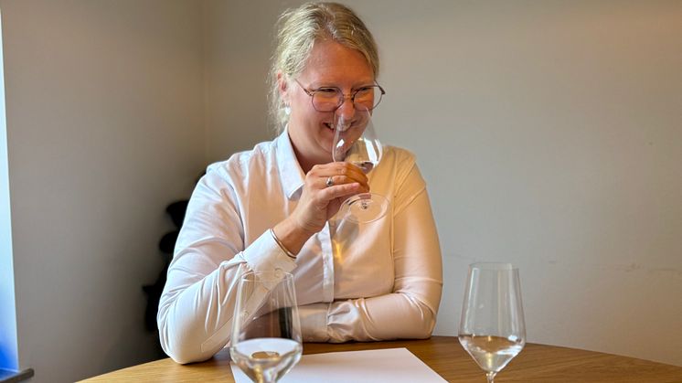 Sommelieren Emma Ziemann håller ett stort glas framför ansiktet. I glaset finns krisvatten. Hon luktar på vattnet.
