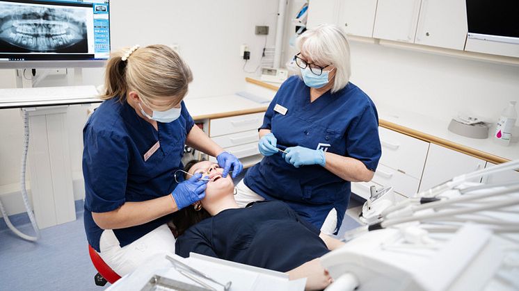 Bild på patient som blir behandlad av tandläkare och tandsköterska. 