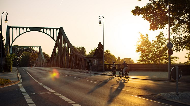 Glienicke Bridge facing Potsdam during the golden hour, bathed in warm orange light.