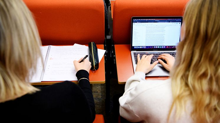 Två studenter antecknar i sina datorer under en föreläsning.