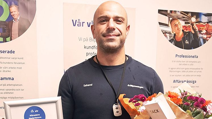 Man som håller i diplom och blommor