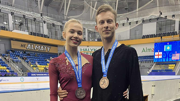 Isdanspar med bronsmedaljer runt halsen. Mannen är klädd i svart och kvinnan i vinrött.