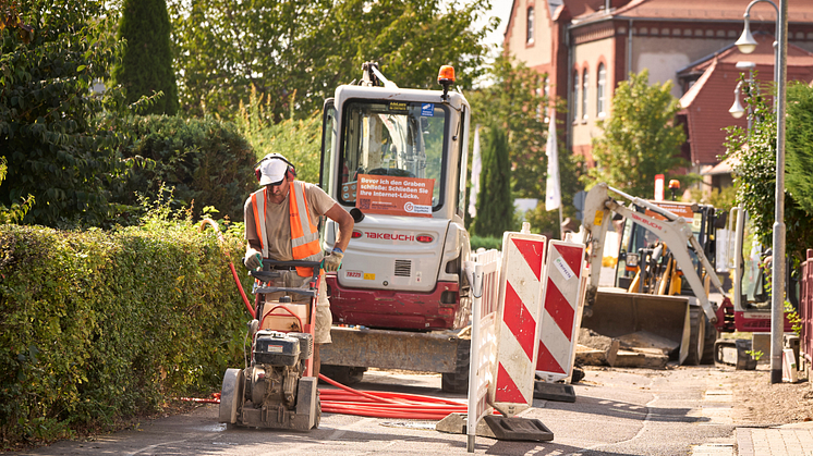 Ein Arbeiter auf einer abgesperrten Baustelle mit zwei Baggern.