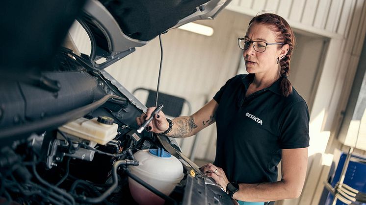 En tekniker från Besikta kontrollerar en fordonsmotor.