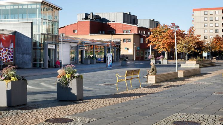 Vy över Hjällbo Centrum. En man sitter på en bänk i bakgrunden.