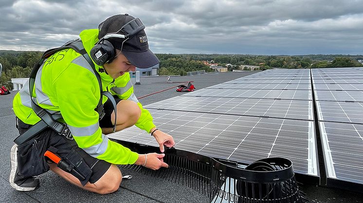 Montör från Nordic Solar installerar solpaneler på ett tak, dimensionerade för hög egenförbrukning.