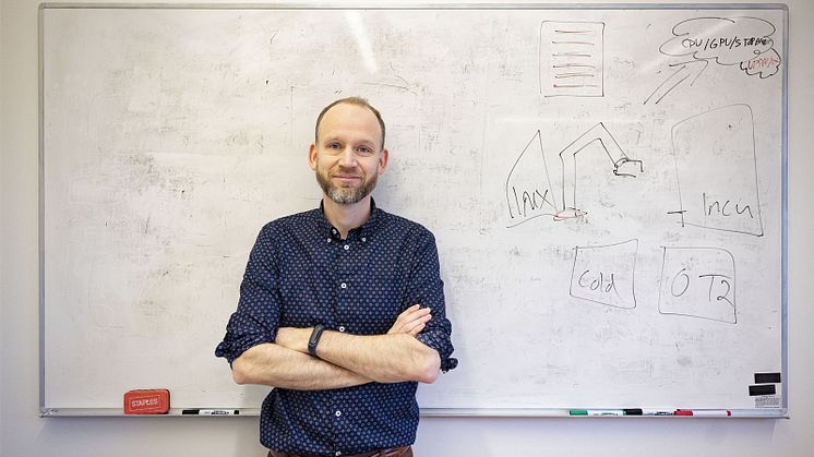 Ola Spjuth står framför en vit tavla där det ritats lite i ena hörnet. Det är svårt att se vad ritningen föreställer.