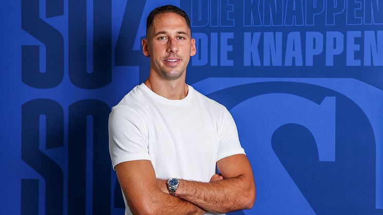 Nikola Katic steht vor einer blauen Schalke Wand