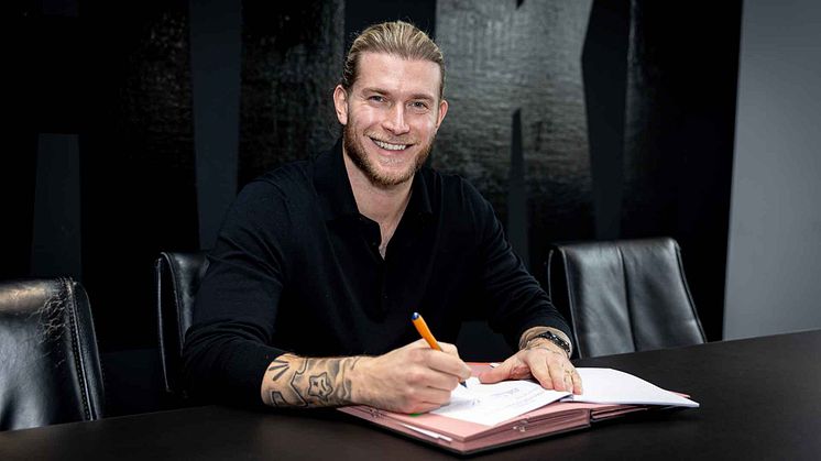 Loris Karius unterschreibt einen Vertrag vor einer schwarzen Wand