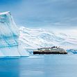 A HX ship is pictured between Antarctica, between two large icebergs in Antarctica. 
