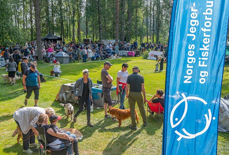En folkemengde samlet rundt en utstillingsring på hundeutstilling. Et banner med Norges jeger- og fiskerforbund i forgrunnen.