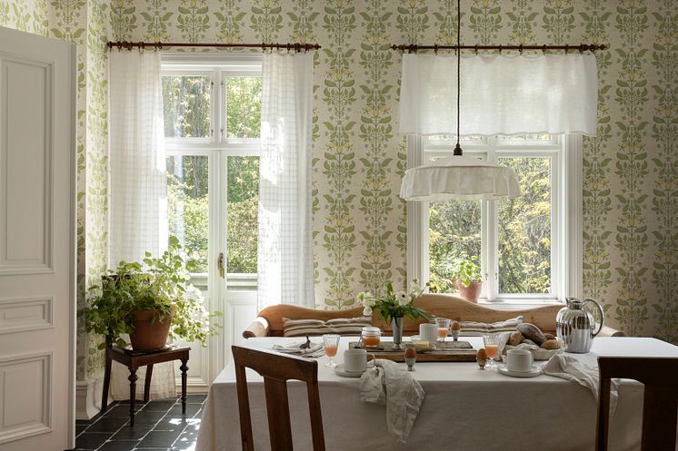 Ljus tapet med rosrankor i gammaldags kök där en mysig frukost är framdukad.