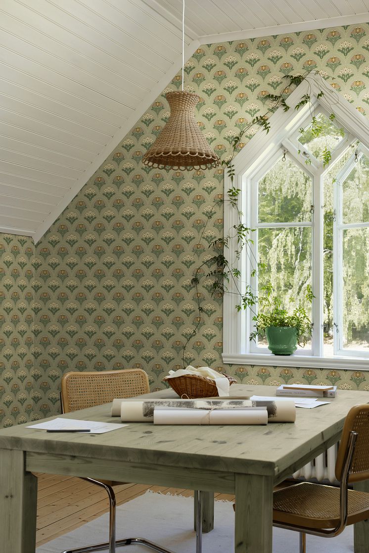 Beige tapet med blommor som skapar ett bågmönster i terrakotta och grönt i kreativt arbetsrum.