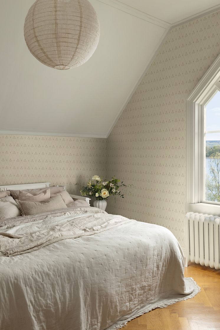 Beige tapet med trellsimönster i ljust och luftigt sovrum.