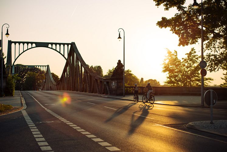 Glienicke Bridge facing Potsdam during the golden hour, bathed in warm orange light.